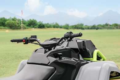 Photo of Modern quad bike on green grass in field, closeup