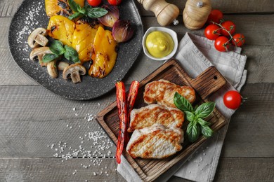 Photo of Delicious grilled meat and vegetables served on wooden table, flat lay