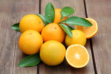 Many ripe oranges and green leaves on wooden table