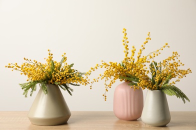 Beautiful mimosa flowers in vases on wooden table