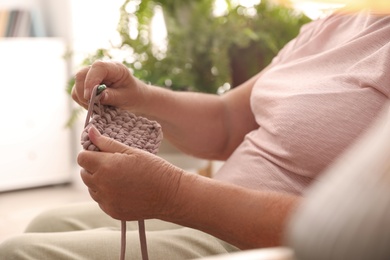 Photo of Elderly woman crocheting at home, closeup. Creative hobby