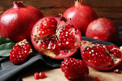 Photo of Ripe pomegranates on wooden board, closeup. Tasty fruits