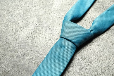 Photo of One blue necktie on grey textured background, closeup. Space for text