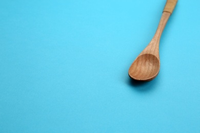 Photo of Clean empty wooden spoon on blue background, space for text