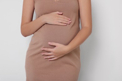 Photo of Pregnant woman in beige dress on white background, closeup