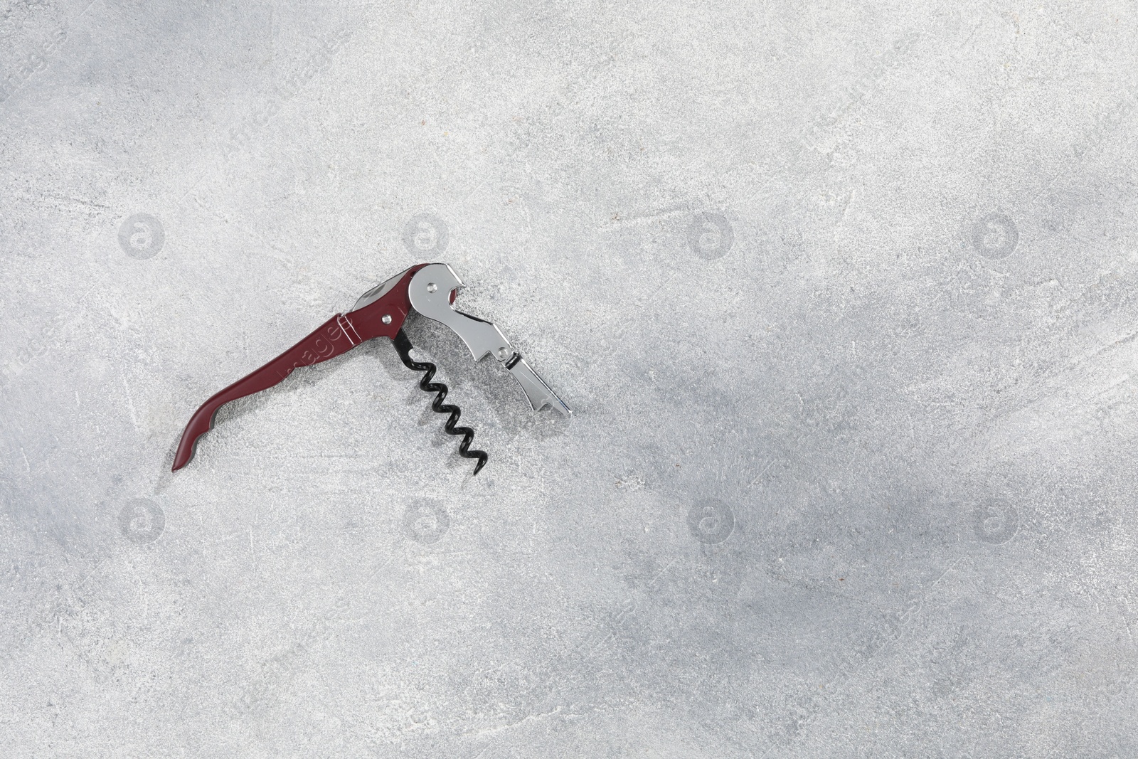 Photo of One corkscrew (sommelier knife) on grey textured table, top view. Space for text