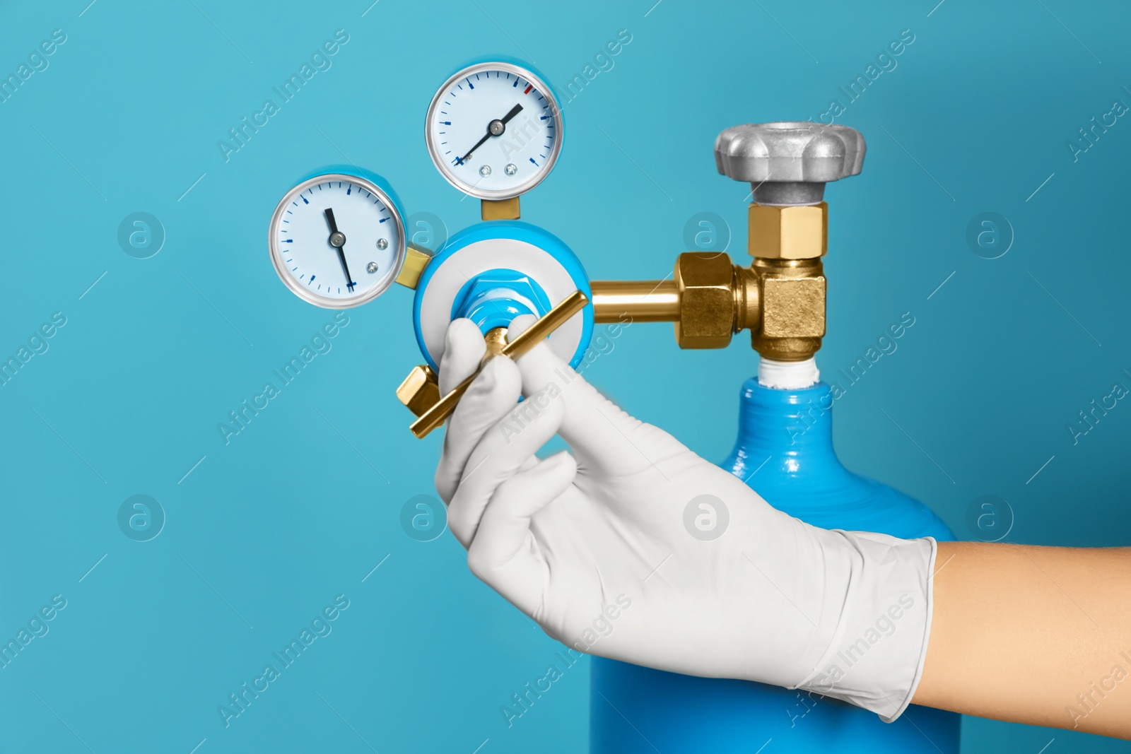 Photo of Medical worker checking oxygen tank on light blue background, closeup