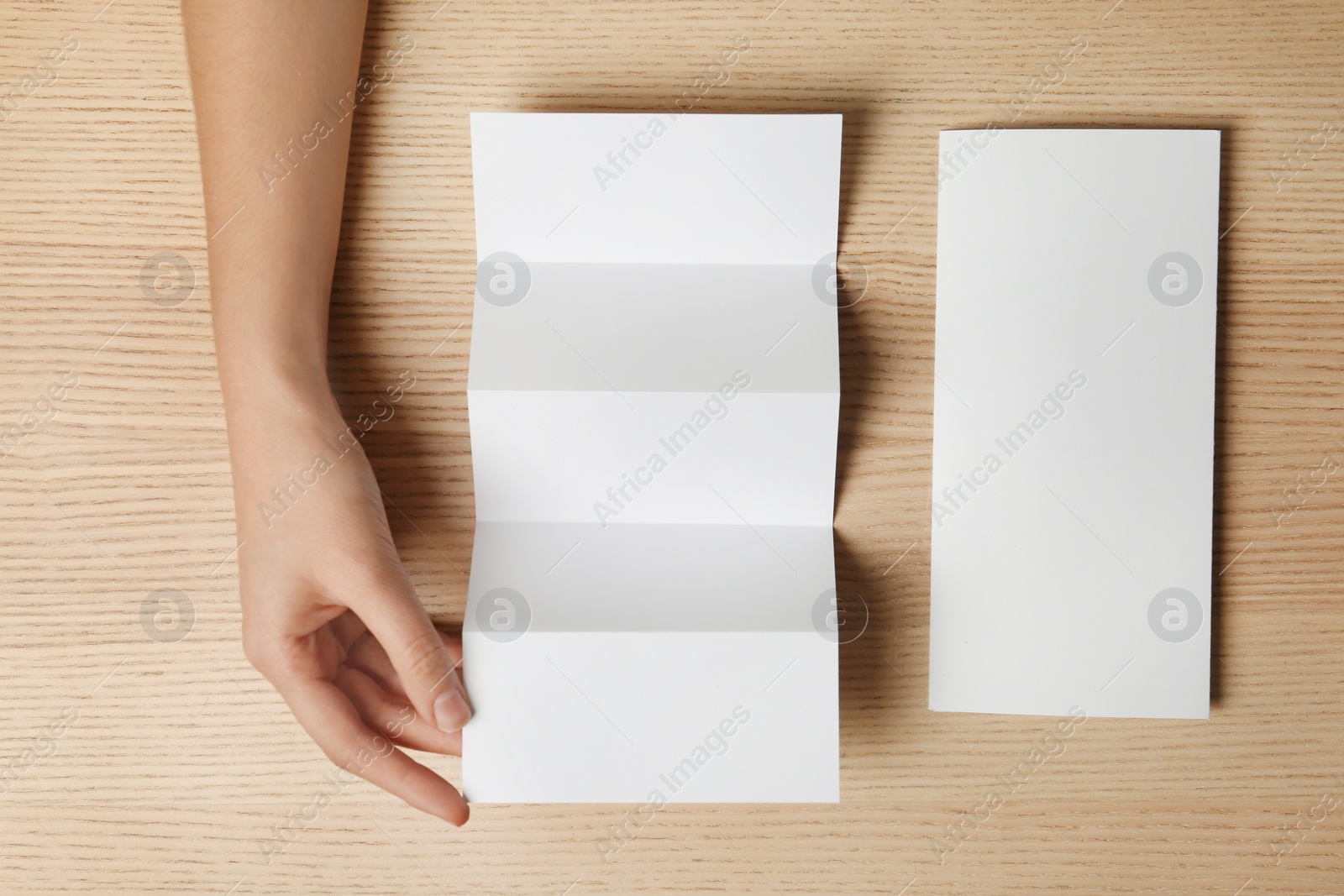 Photo of Woman with two blank brochures on wooden background, top view. Mockup for design