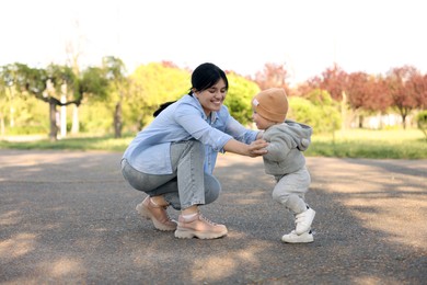 Mother teaching her baby how to walk outdoors