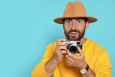 Man with camera on light blue background, space for text. Interesting hobby