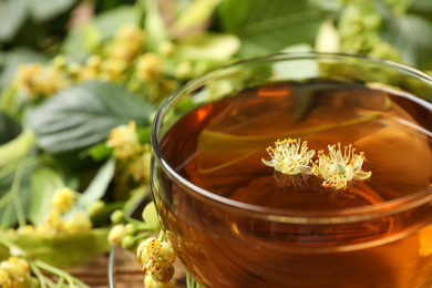 Photo of Cup of tea with linden blossom on blurred background, closeup