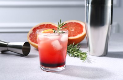 Photo of Delicious cocktail, grapefruit, rosemary and bartender equipment on light grey table