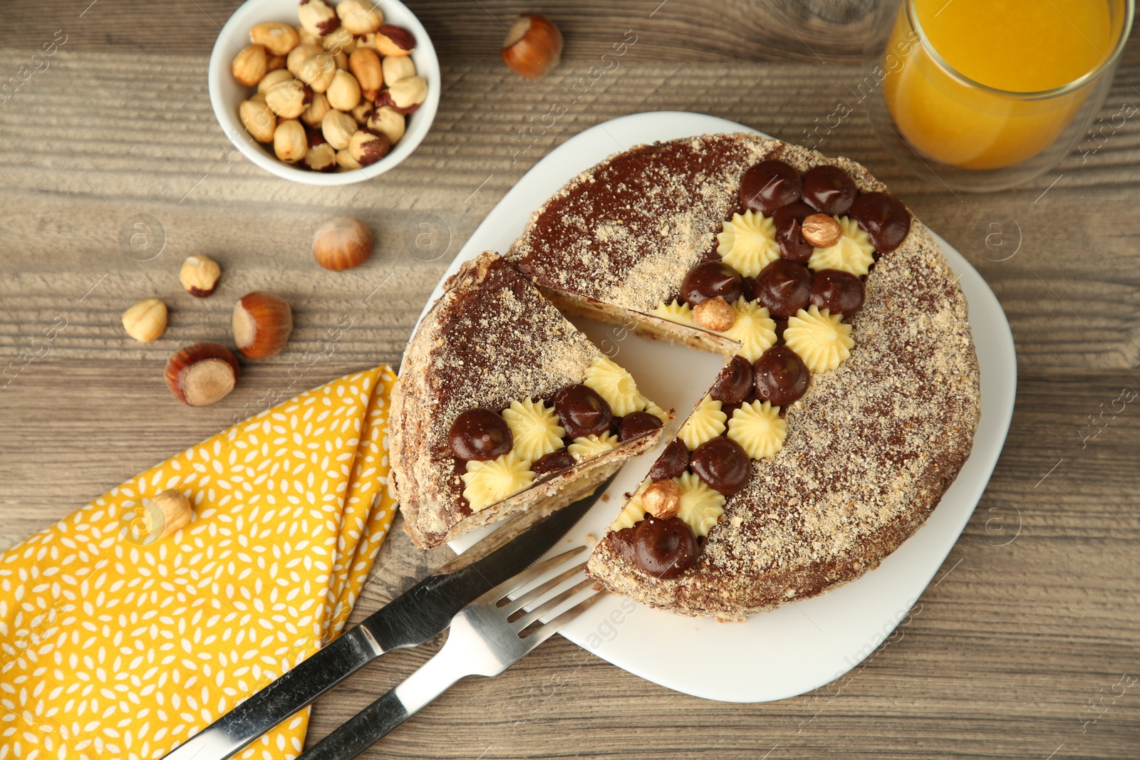 Photo of Delicious Kyiv Cake decorated with cream and hazelnuts served on wooden table, above view