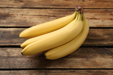 Photo of Bunch of ripe sweet yellow bananas on wooden table