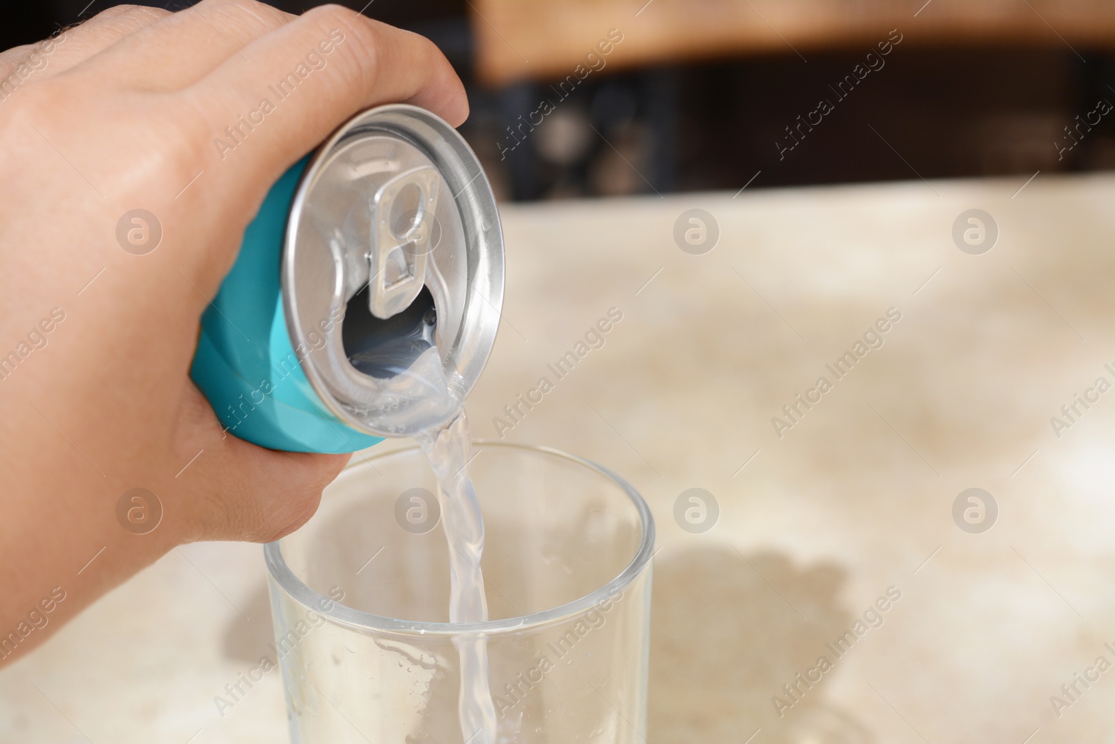 Photo of Woman pouring drink from aluminum can into glass at table, closeup. Space for text