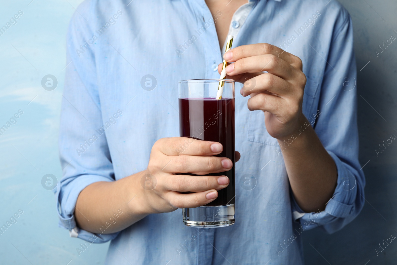 Image of Woman with glass of juice on light blue, closeup 