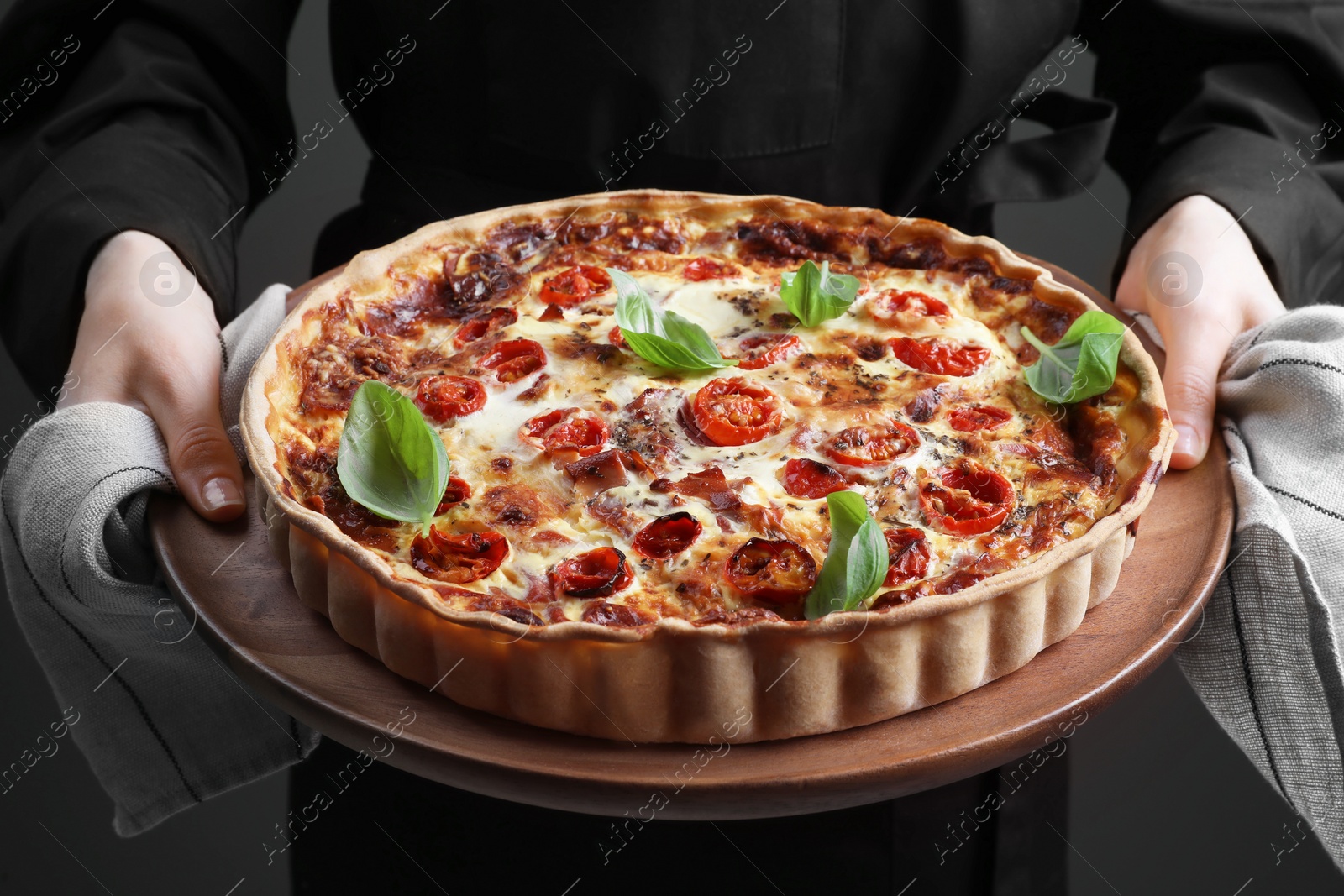 Photo of Woman holding delicious homemade quiche with prosciutto, closeup