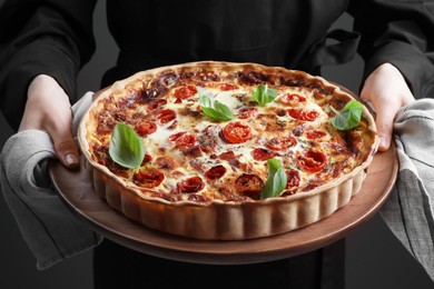 Woman holding delicious homemade quiche with prosciutto, closeup