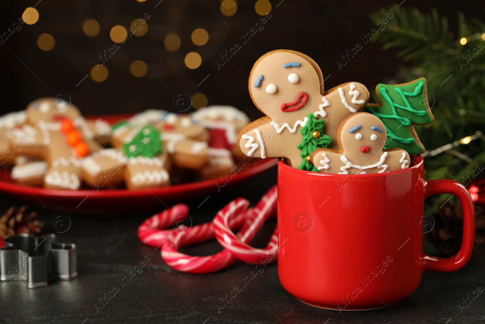 Photo of Delicious homemade Christmas cookies on black table against blurred festive lights. Space for text