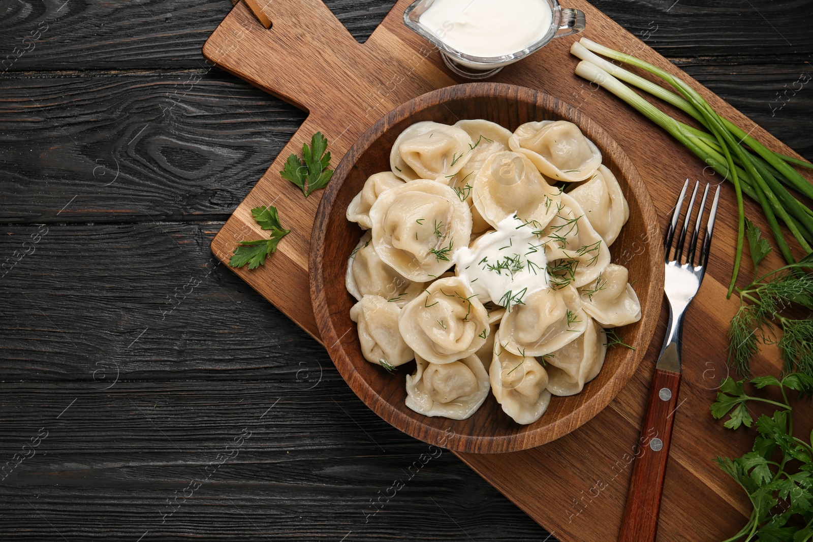 Photo of Flat lay composition with tasty dumplings on black wooden table