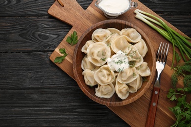 Photo of Flat lay composition with tasty dumplings on black wooden table