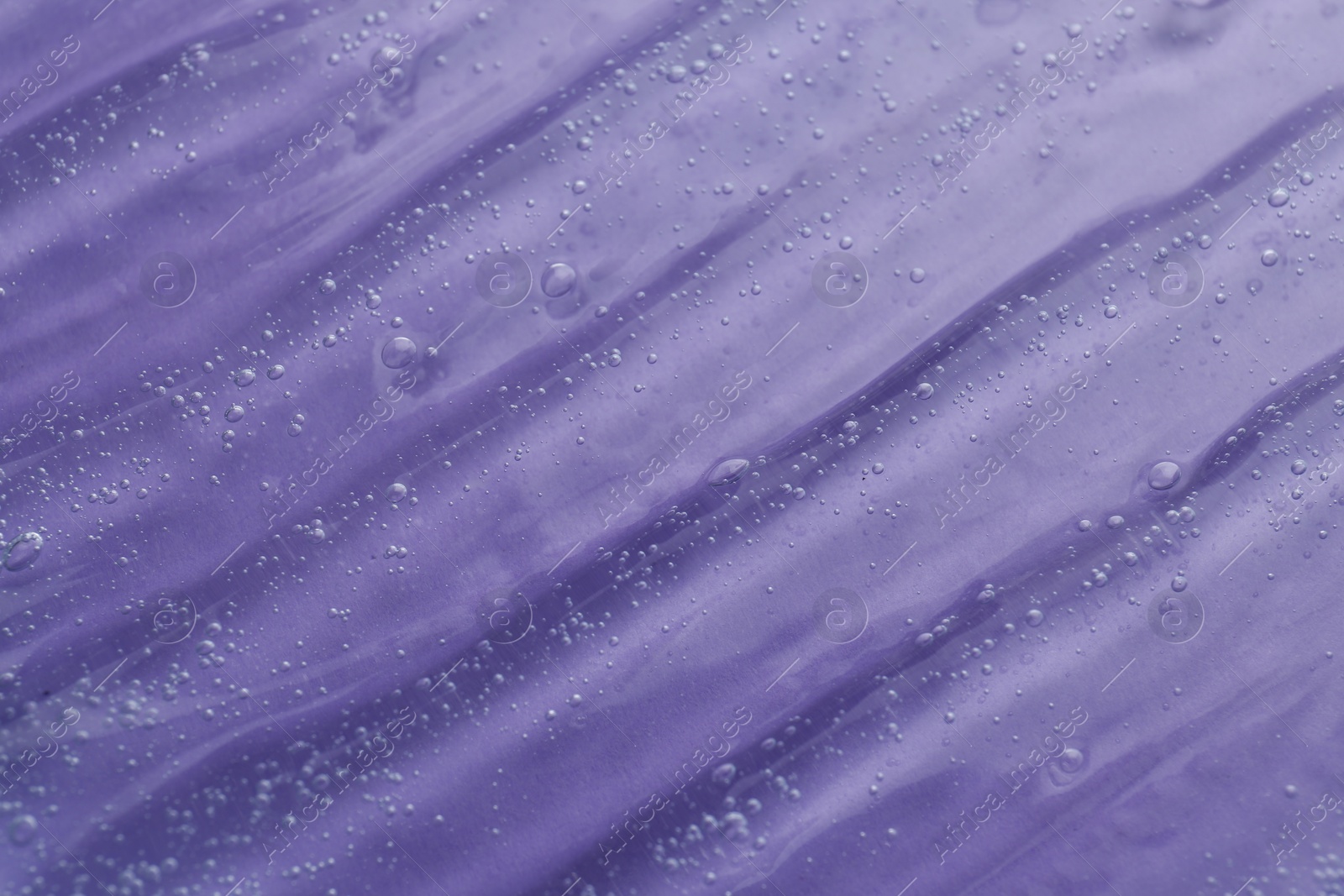 Photo of Texture of transparent shower gel on violet background, closeup