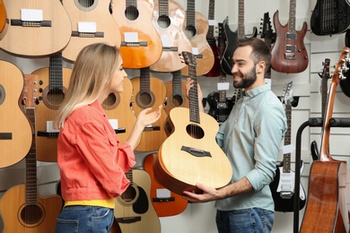 Photo of Young people choosing guitar in music store