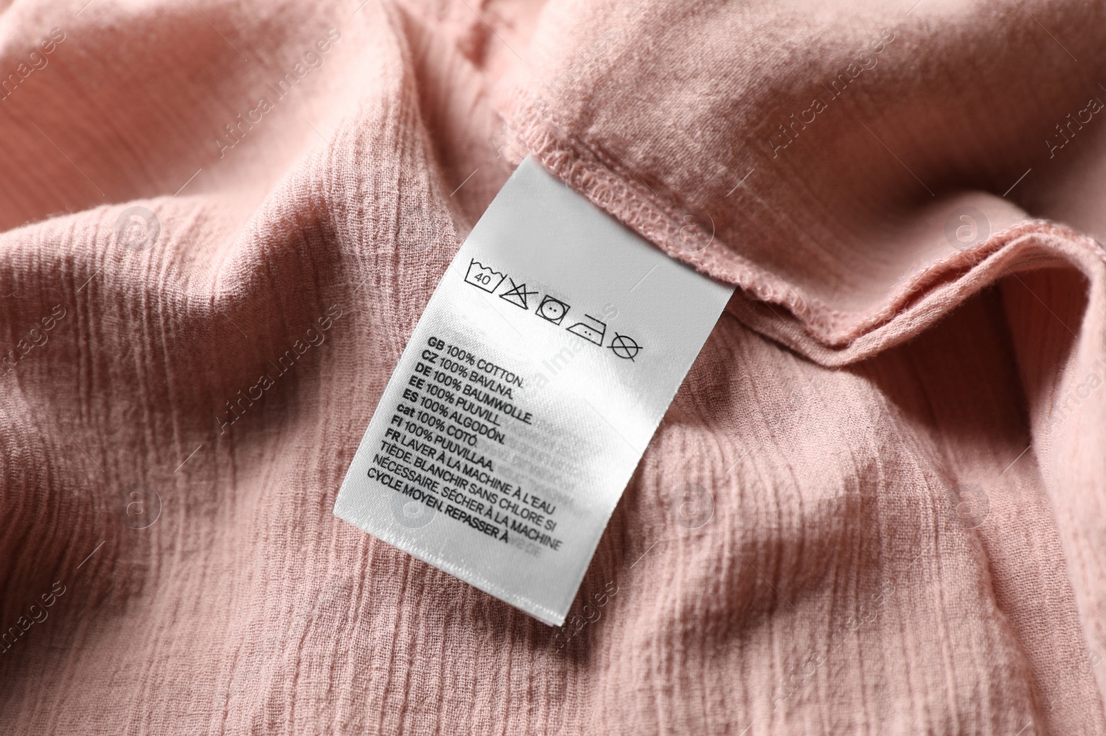 Photo of Clothing label on beautiful pink garment, closeup view