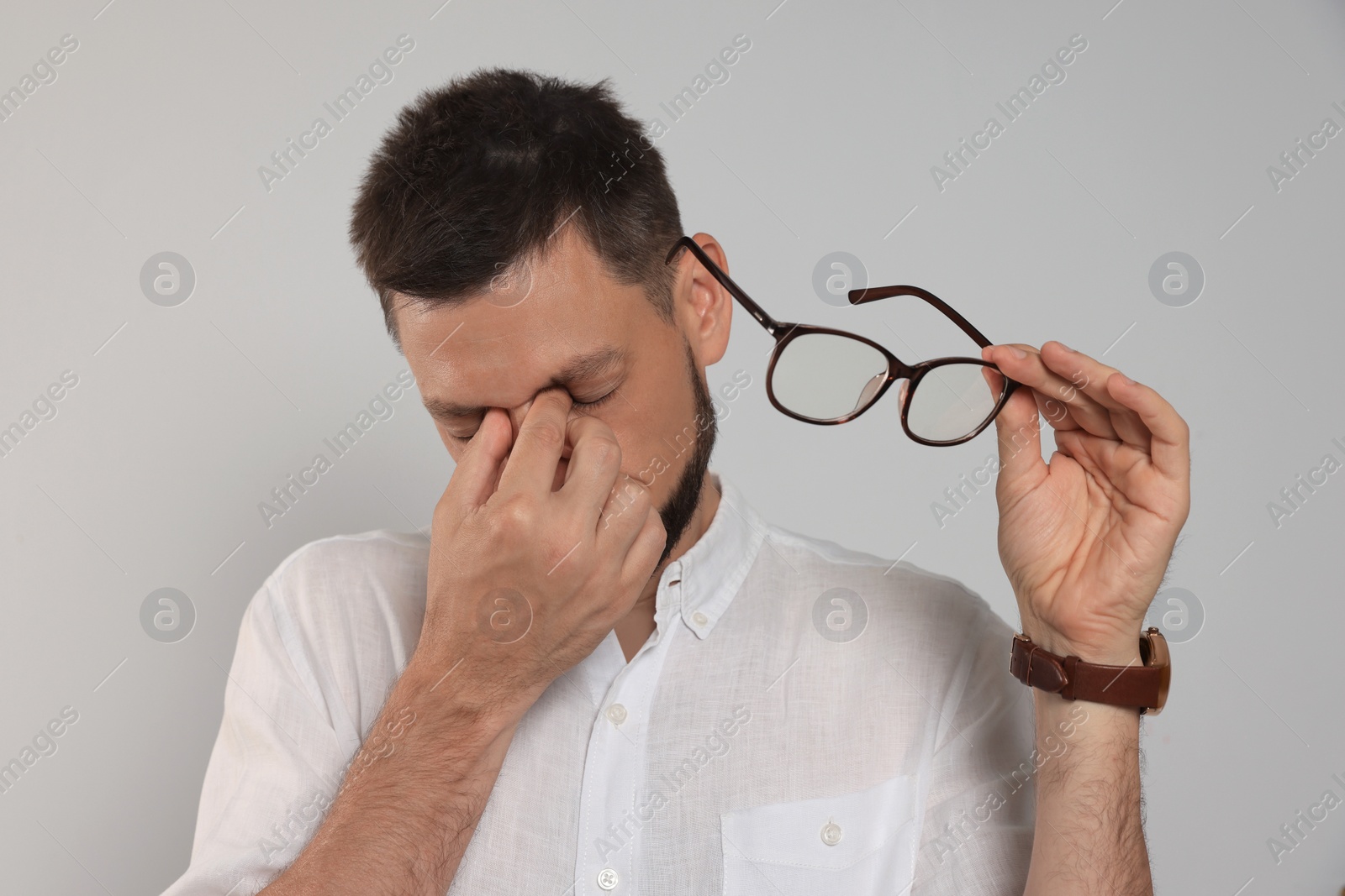 Photo of Man suffering from eyestrain on light background