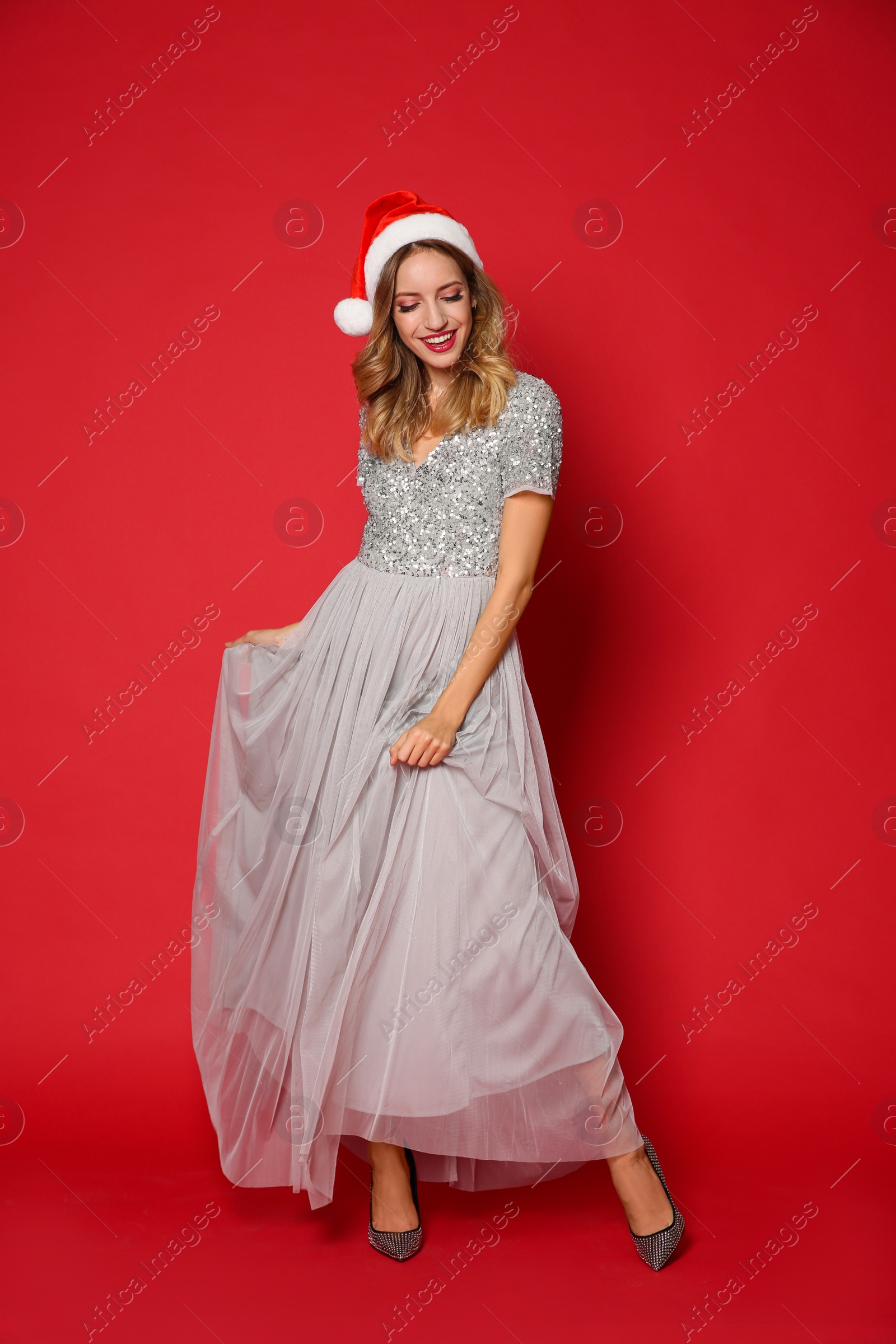 Photo of Happy woman in Santa hat on red background. Christmas party
