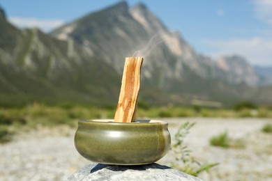 Photo of Palo santo stick on stone surface in high mountains, closeup
