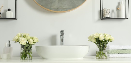 White sink between beautiful roses and toiletries in bathroom