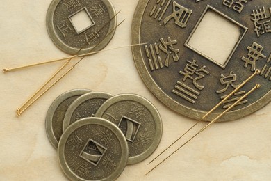 Acupuncture needles and Chinese coins on paper, flat lay