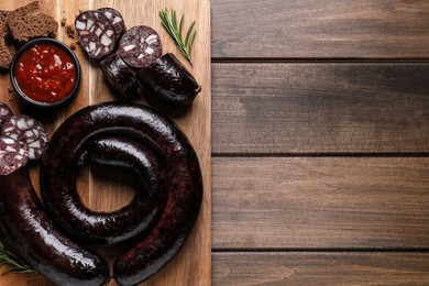 Photo of Tasty blood sausages served on wooden table, top view. Space for text