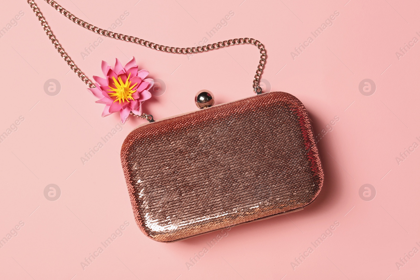 Photo of Stylish shiny bag and flower on pink background, top view