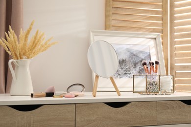 Photo of Dressing table with mirror, cosmetic products and jewelry in makeup room