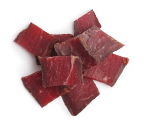 Pieces of delicious beef jerky on white background, top view