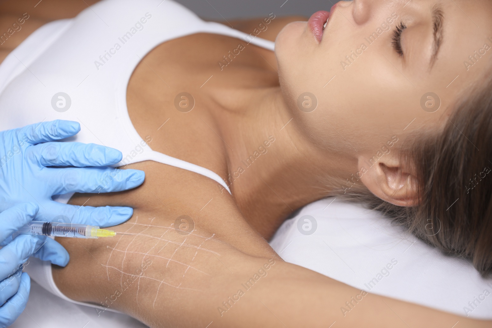 Photo of Young woman getting armpits injection in salon, closeup