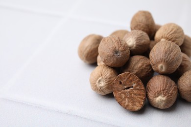 Photo of Heap of nutmegs on white table. Space for text