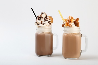 Photo of Mason jars with delicious milk shakes on white background