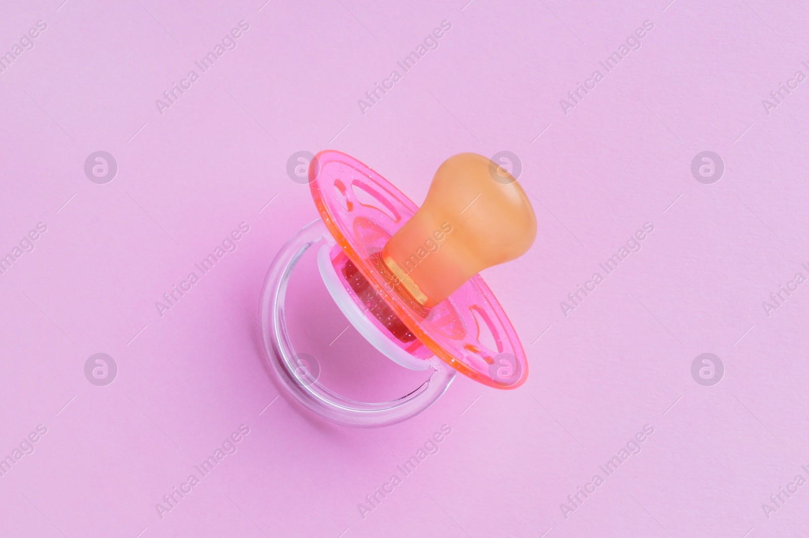 Photo of New baby pacifier on pink background, top view