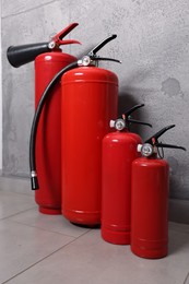 Photo of Four red fire extinguishers near grey wall