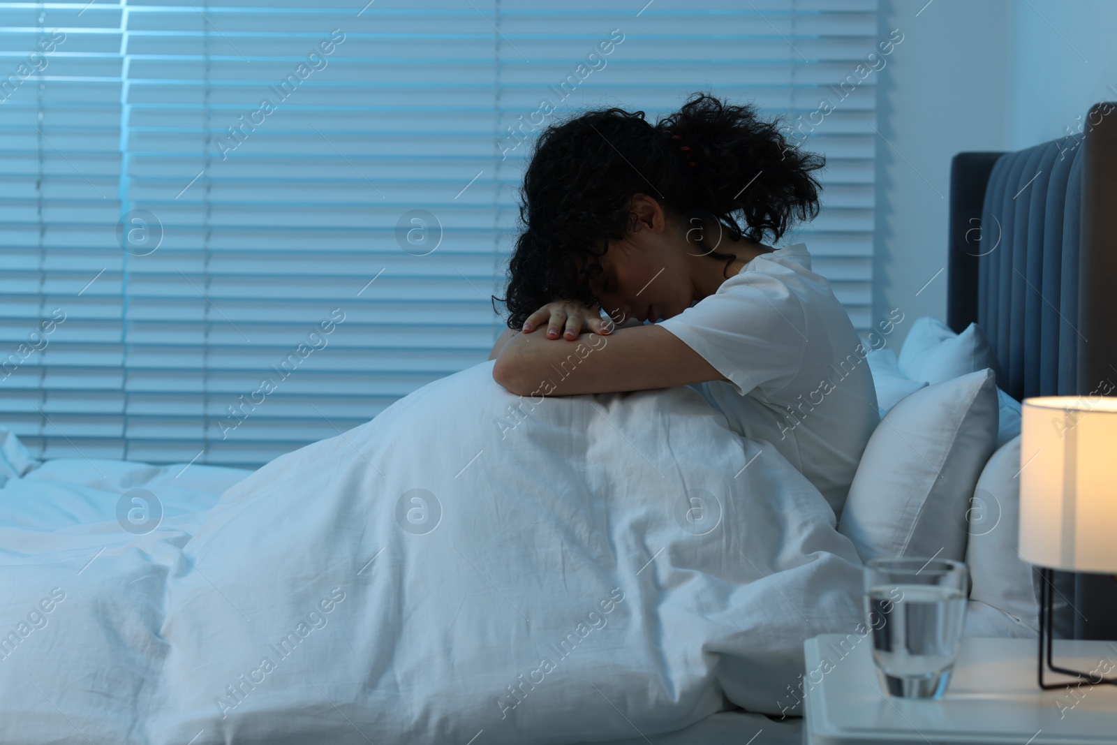 Photo of Young woman suffering from headache in bed at night