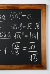 Blackboard with different mathematical formulas written with chalk on white wall
