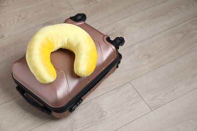 Photo of Yellow travel pillow and suitcase on floor, space for text