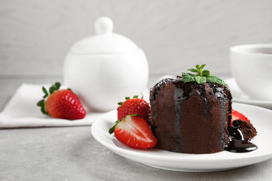 Delicious warm chocolate lava cake with mint and strawberries on table. Space for text