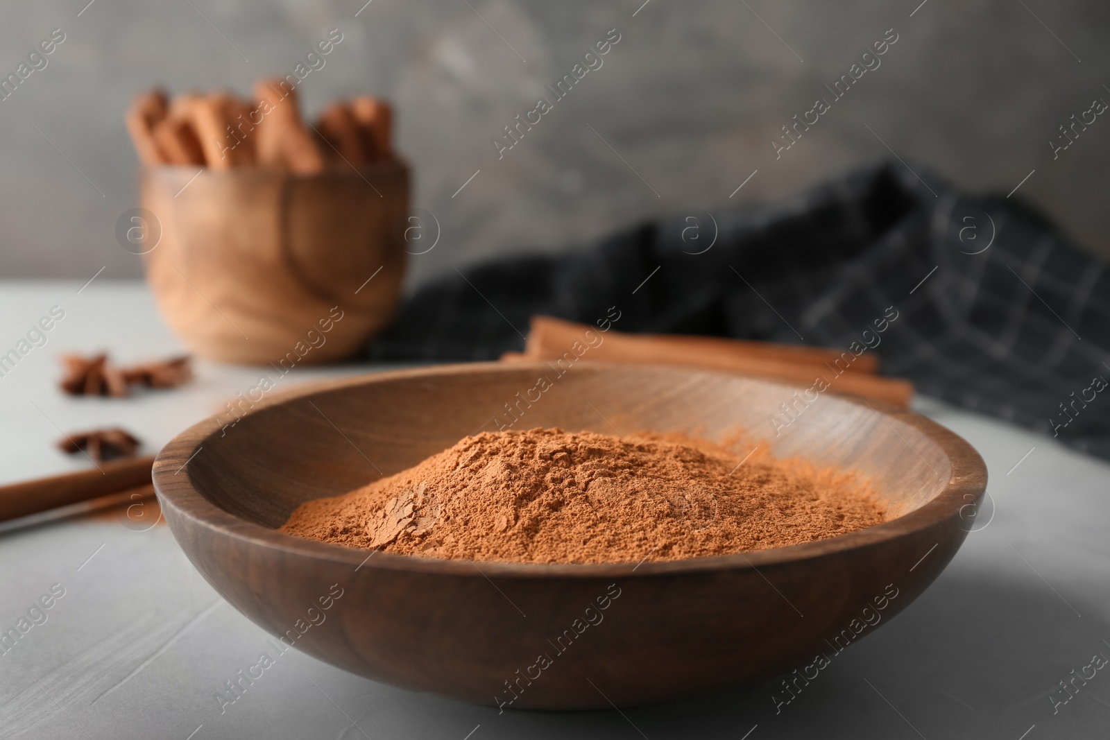Photo of Bowl with aromatic cinnamon powder on table
