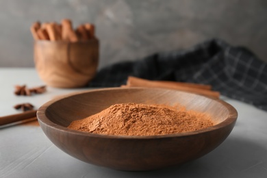 Photo of Bowl with aromatic cinnamon powder on table