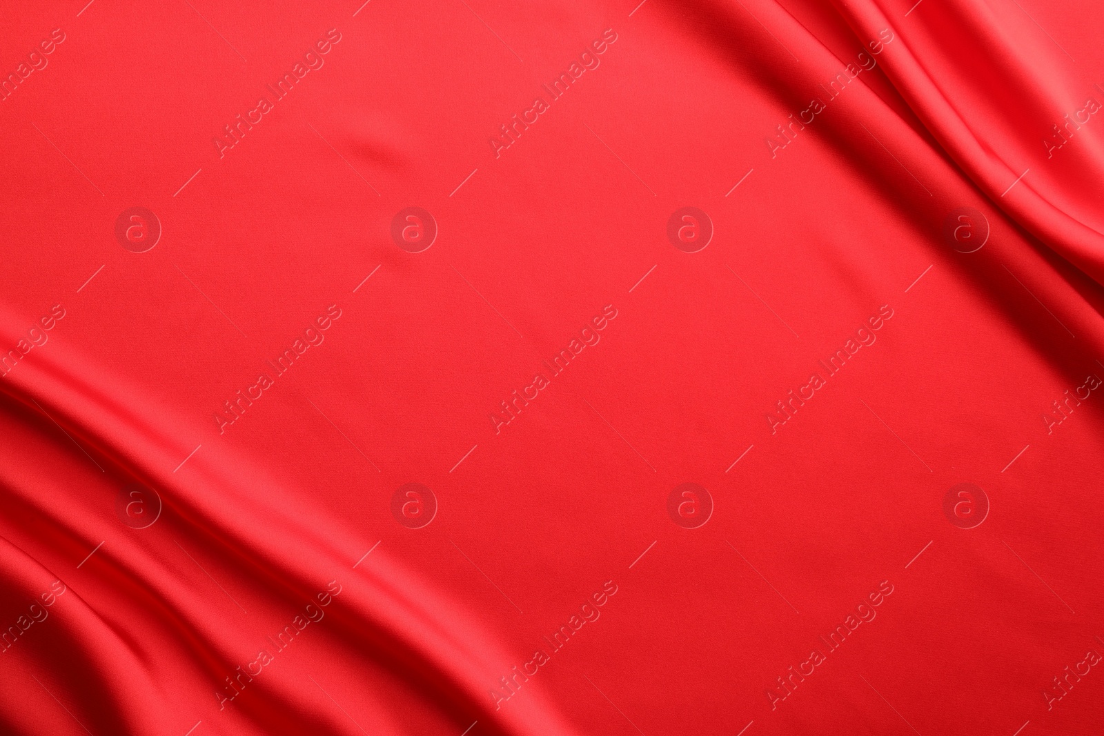 Photo of Crumpled red silk fabric as background, top view. Space for text