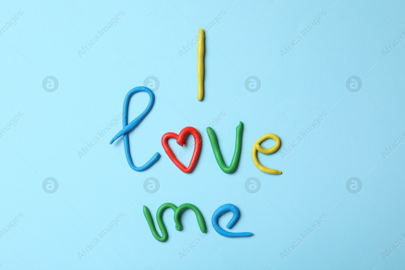 Photo of Phrase I Love Me made of modelling clay on light blue background, flat lay
